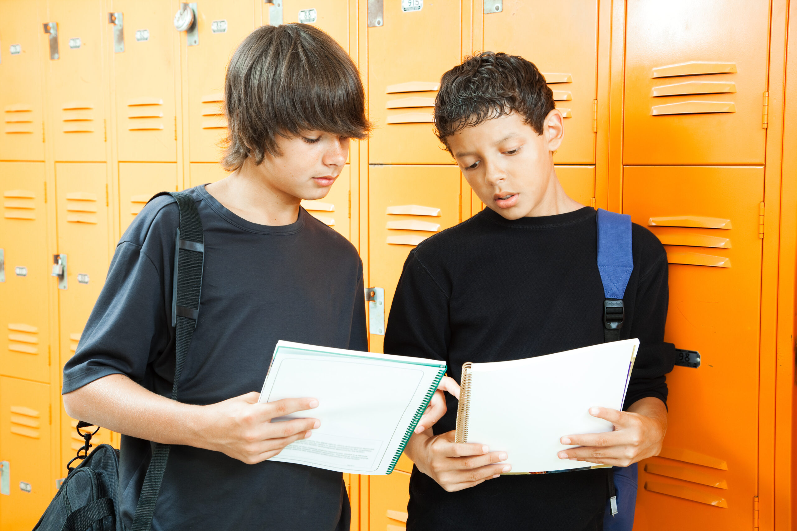 Teenage,Boys,By,Lockers,,Comparing,Answers,In,Their,Homework,Workbooks.